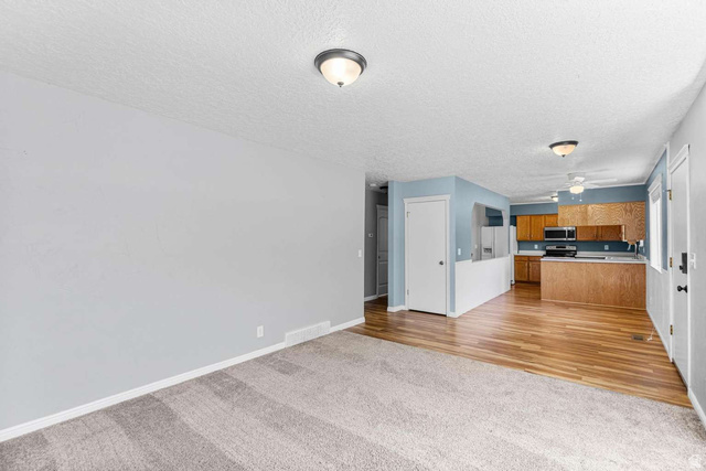 415 East 1150th Street North Logan, UT 84341 - Photo 7 of 38 Open-concept living area with carpeted flooring transitioning to wood-finish flooring