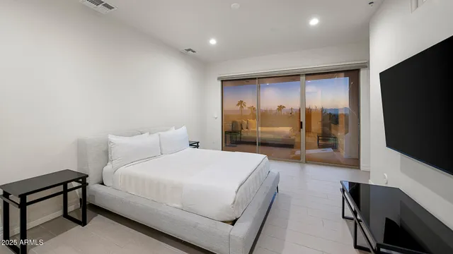a bedroom with a bed and a flat tv screen on wall