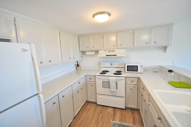a kitchen with a white cabinets a sink a stove a refrigerator and white cabinets