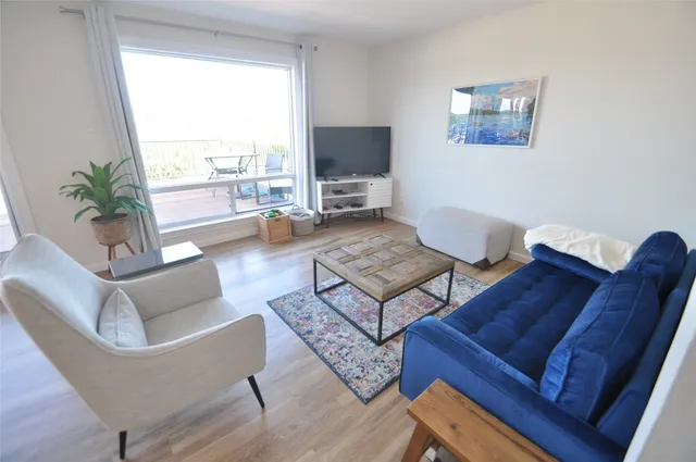 a living room with furniture a flat screen tv and a large window