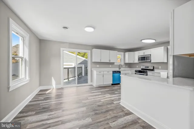a kitchen with stainless steel appliances granite countertop a stove top oven a sink dishwasher a refrigerator and white cabinets with wooden floor