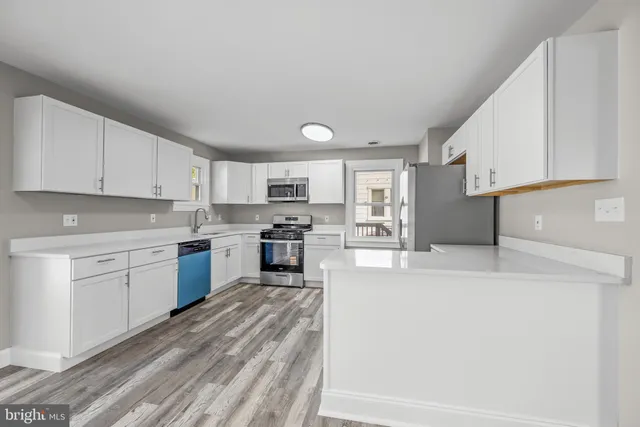 a kitchen with granite countertop a sink stainless steel appliances and white cabinets