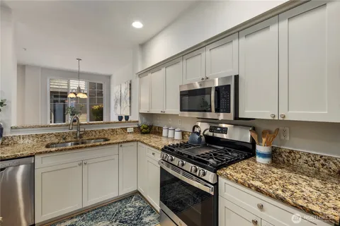 a kitchen with stainless steel appliances granite countertop a stove a sink and a microwave