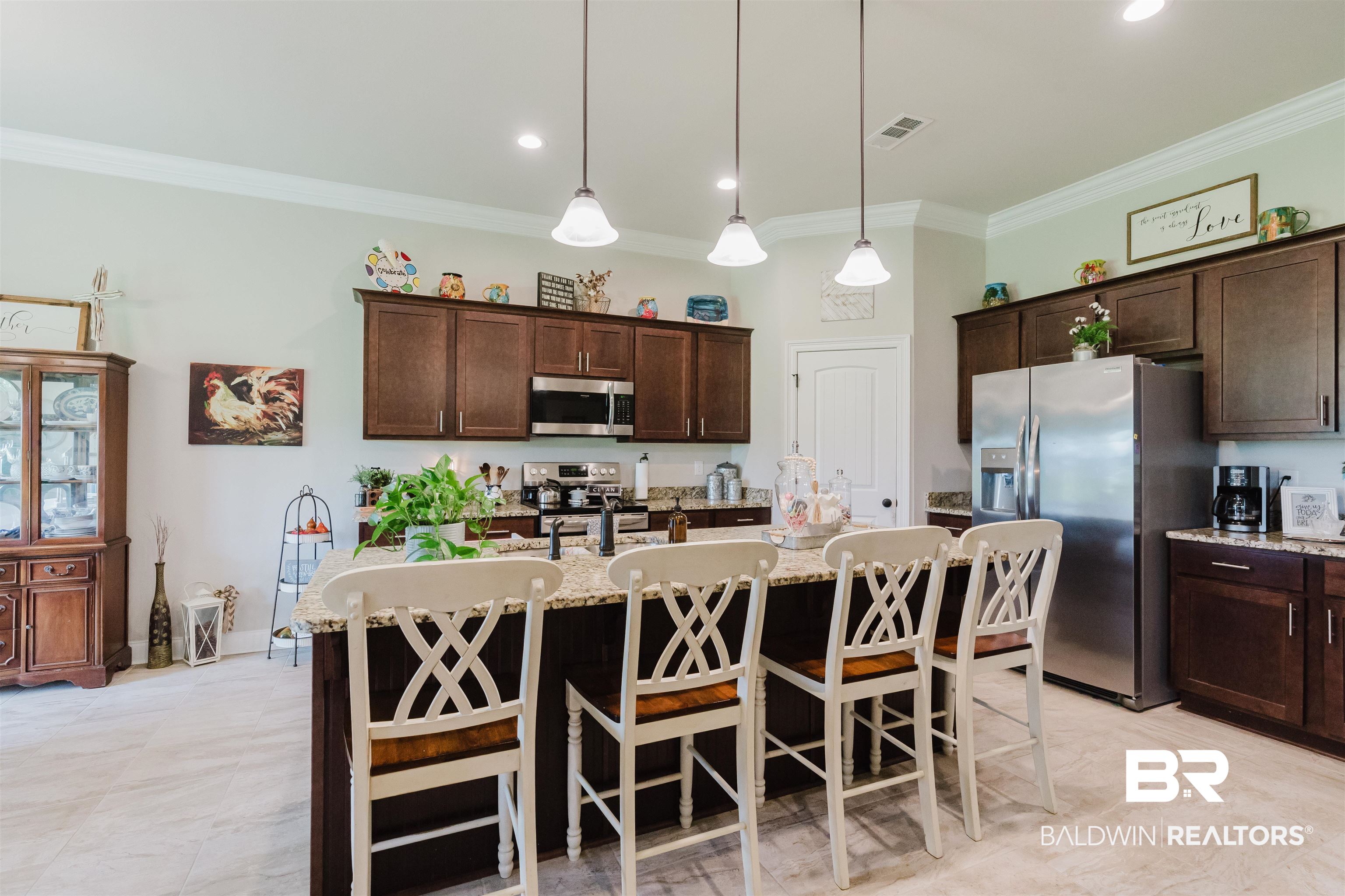 12128 Red Barn Road Fairhope, AL 36532 - Photo 11 of 47 Kitchen with appliances with stainless steel finishes, ornamental molding, dark brown cabinetry, a breakfast bar area, and a center island with sink