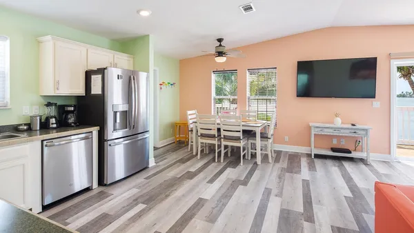 a kitchen with stainless steel appliances a refrigerator a stove a dining table and chairs with wooden floor