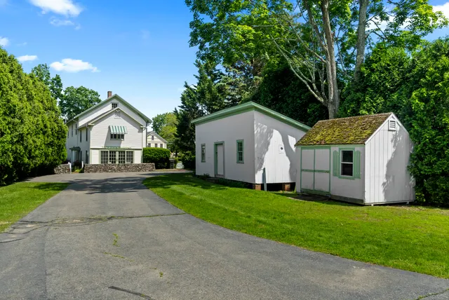 a view of house with a yard and large trees