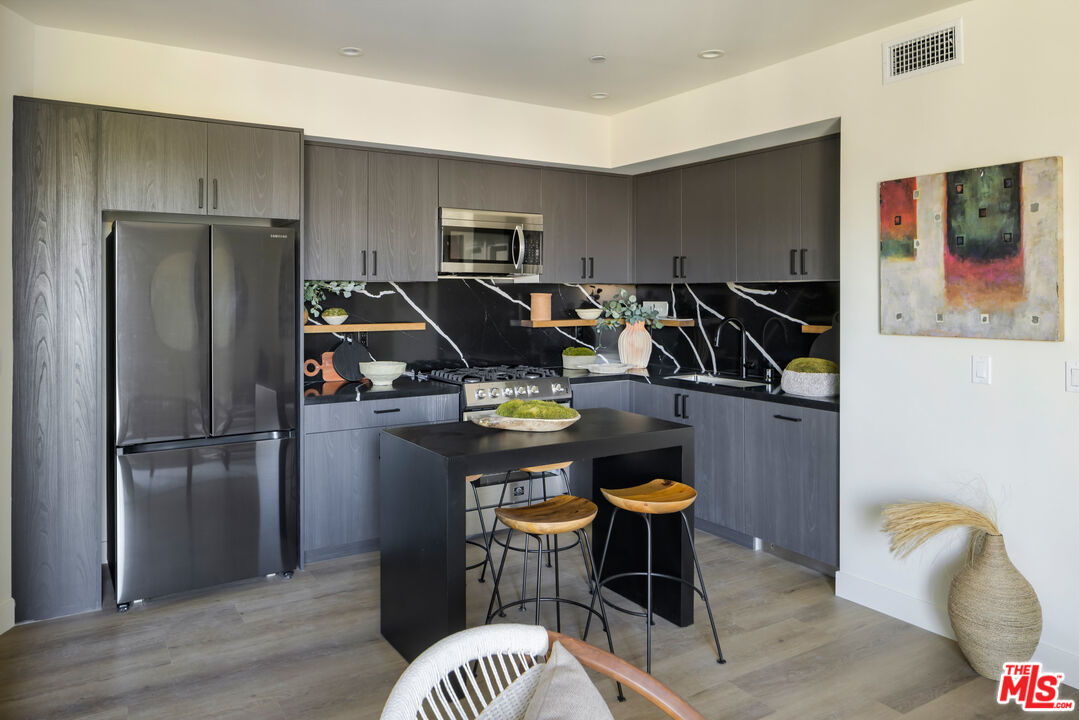 1110 South Spaulding Avenue, Unit 503 Los Angeles, CA 90019 - Photo 7 of 13 a kitchen with stainless steel appliances granite countertop a refrigerator a sink a stove and white cabinets