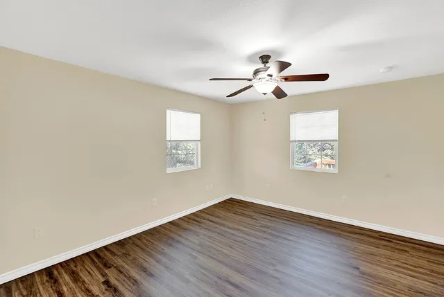 a view of a big room with wooden floor and a ceiling fan