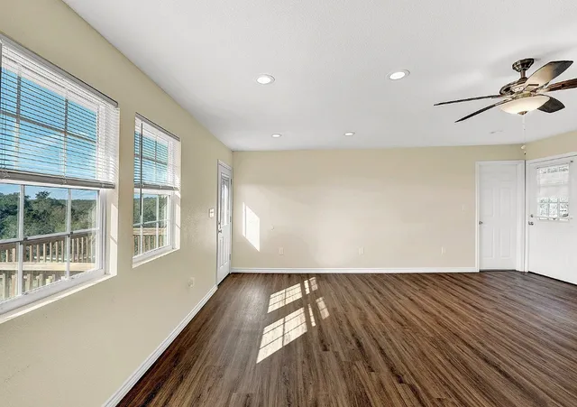 a view of empty room with wooden floor and fan