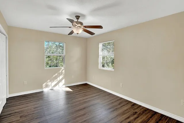 a view of empty room with wooden floor and fan