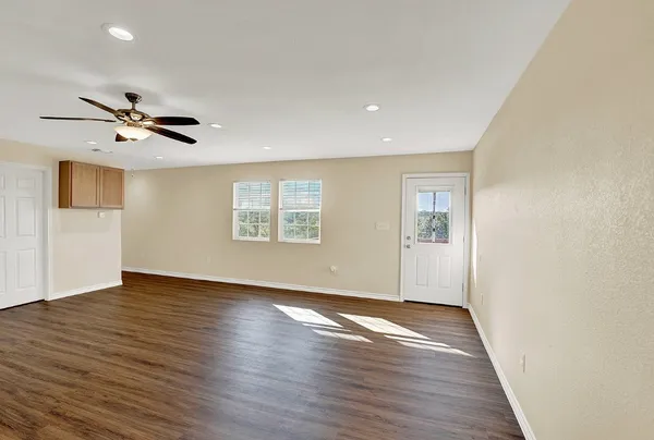 an empty room with wooden floor and a ceiling fan