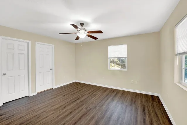 a view of empty room with wooden floor and fan