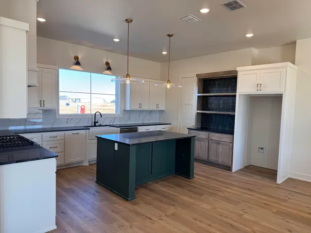 a kitchen with stainless steel appliances granite countertop a sink a stove and a wooden floors