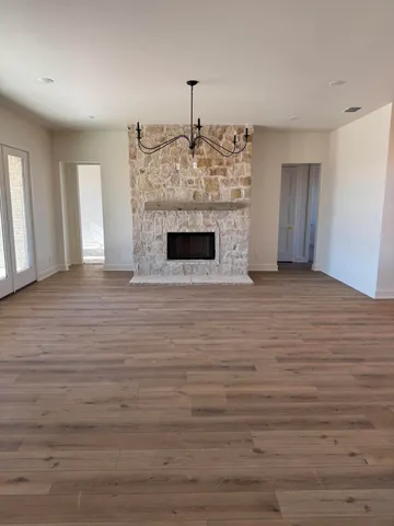 a view of an empty room with wooden floor fireplace and a window