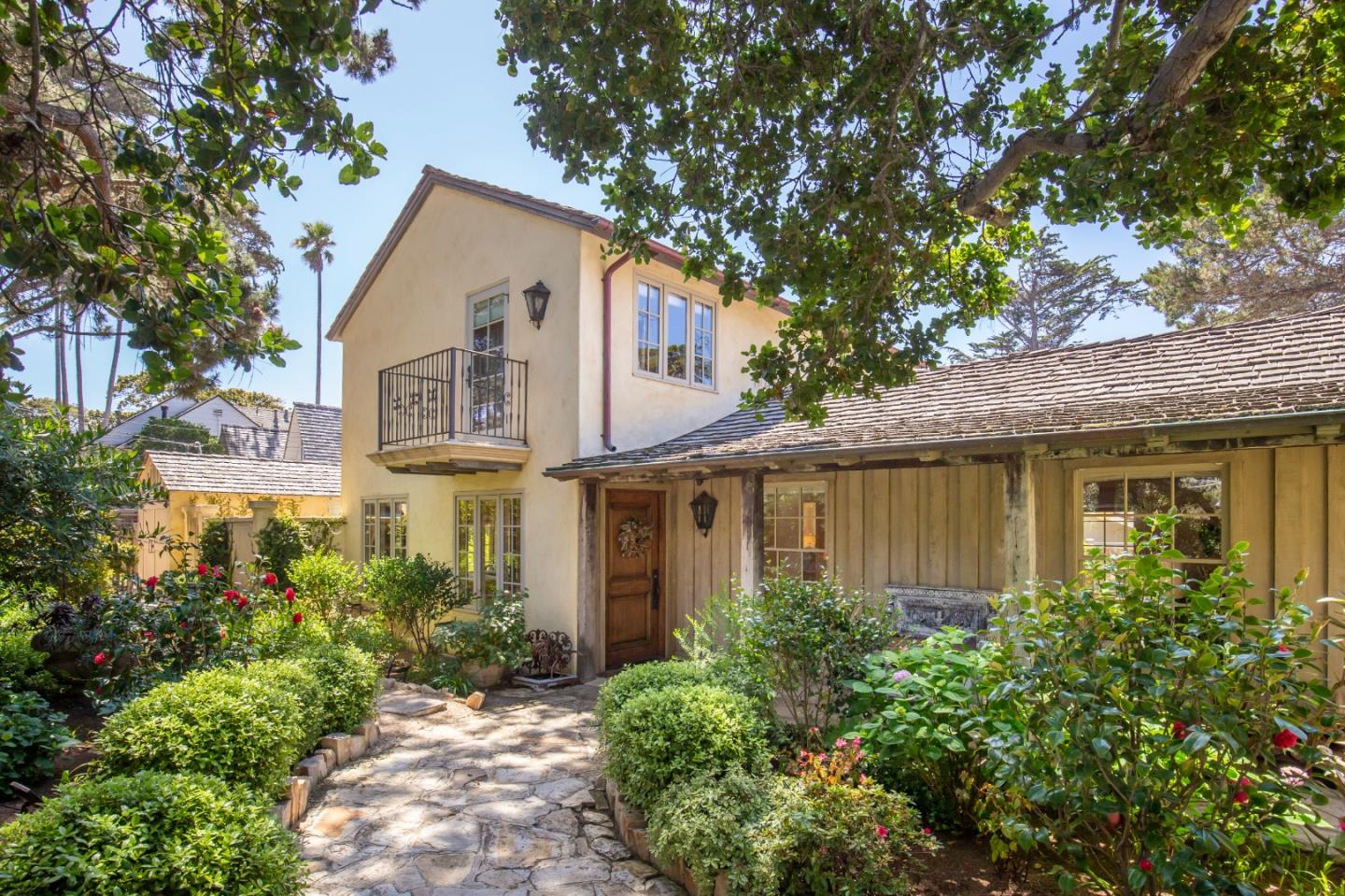 a view of a white house next to a yard with potted plants