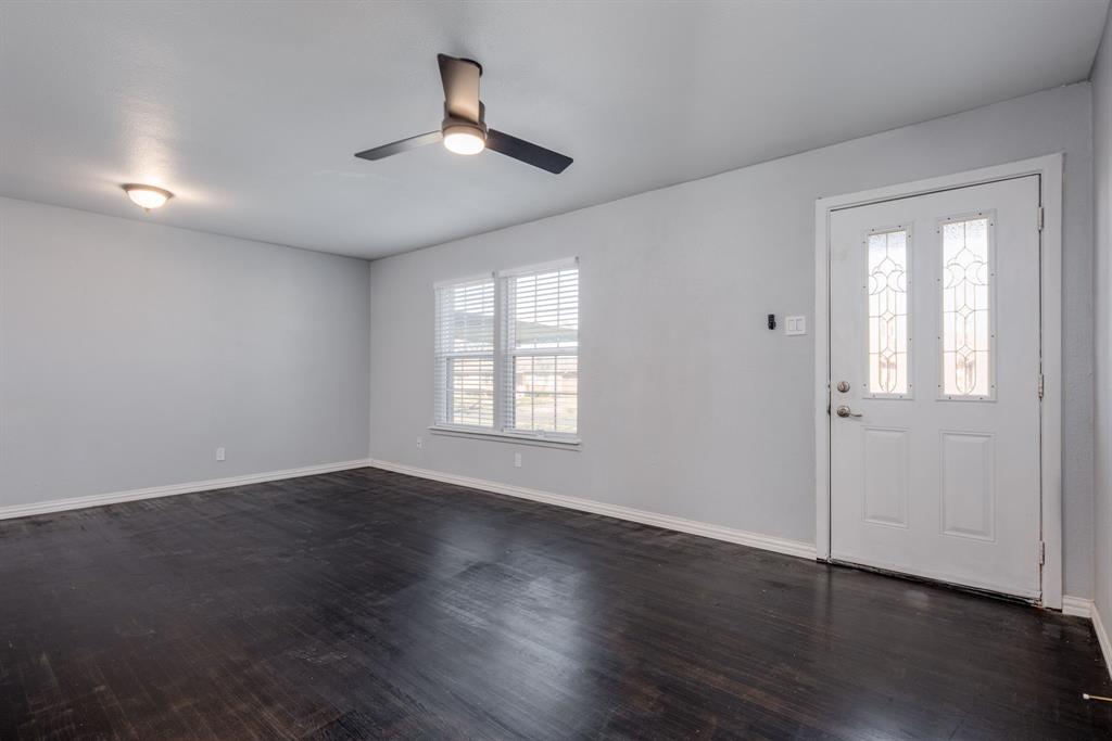 2824 Lockhart Avenue Dallas, TX 75228 - Photo 4 of 16 an empty room with wooden floor chandelier fan and windows