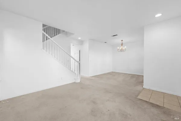 an empty room that has a chandelier fan