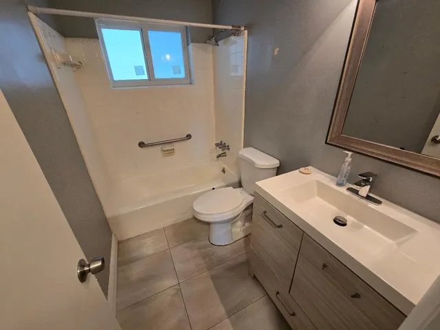 a bathroom with a sink mirror toilet and next to a window