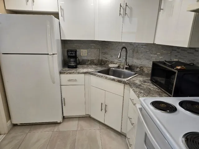 a kitchen with a sink a refrigerator and cabinets