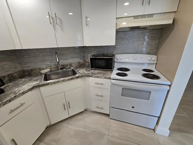 a kitchen with white cabinets and white appliances