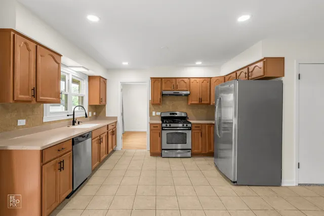 a large kitchen with stainless steel appliances granite countertop a stove a sink and a refrigerator