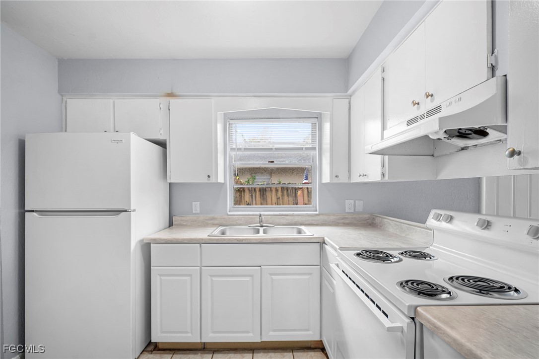 5449 Tenth Avenue Fort Myers, FL 33907 - Photo 9 of 18 a kitchen with kitchen island a sink a stove a refrigerator and white cabinets