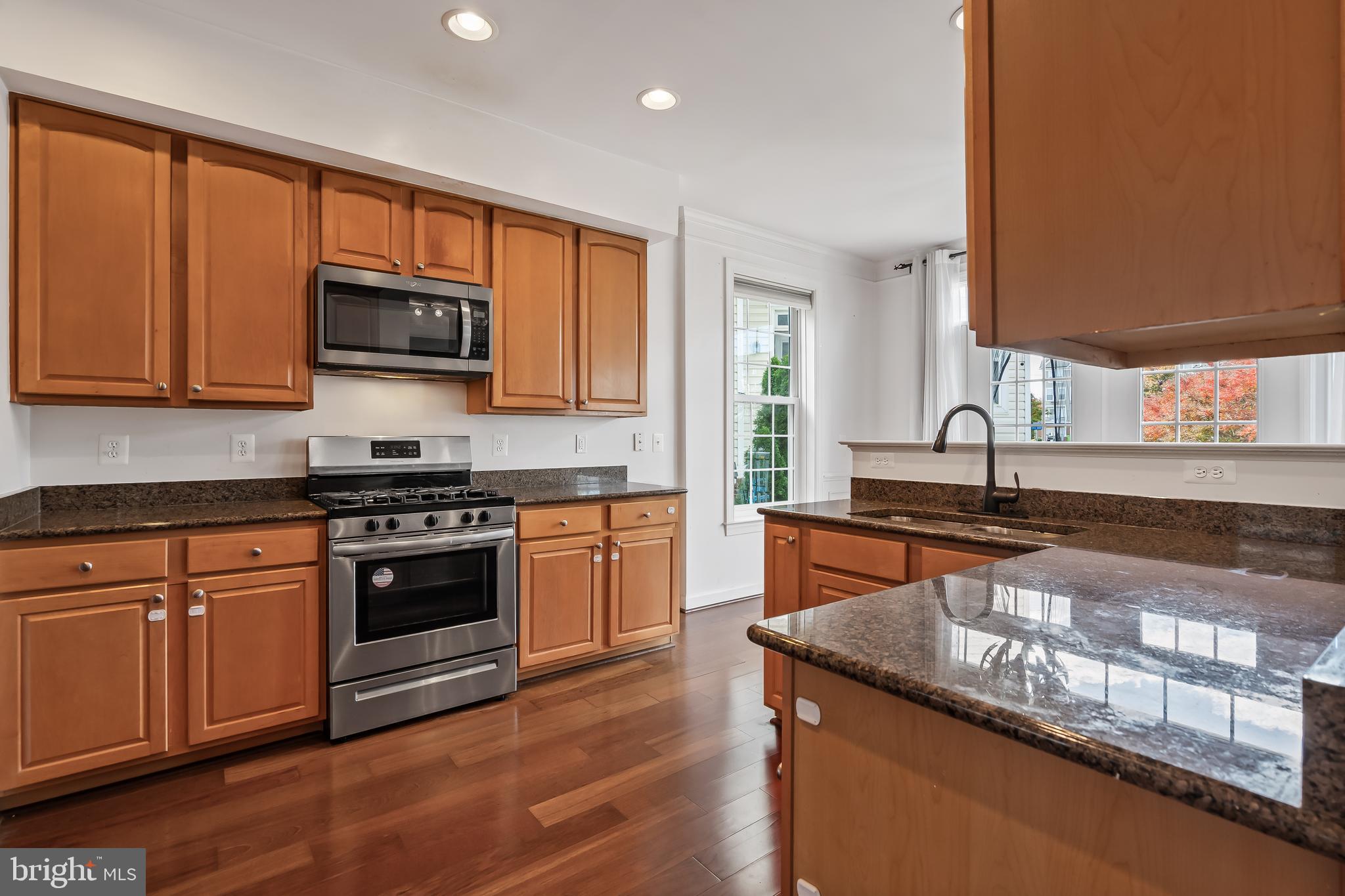 13600 Salk Street, Unit 131 Herndon, VA 20171 - Photo 3 of 34 a kitchen with stainless steel appliances granite countertop a stove a sink and a microwave