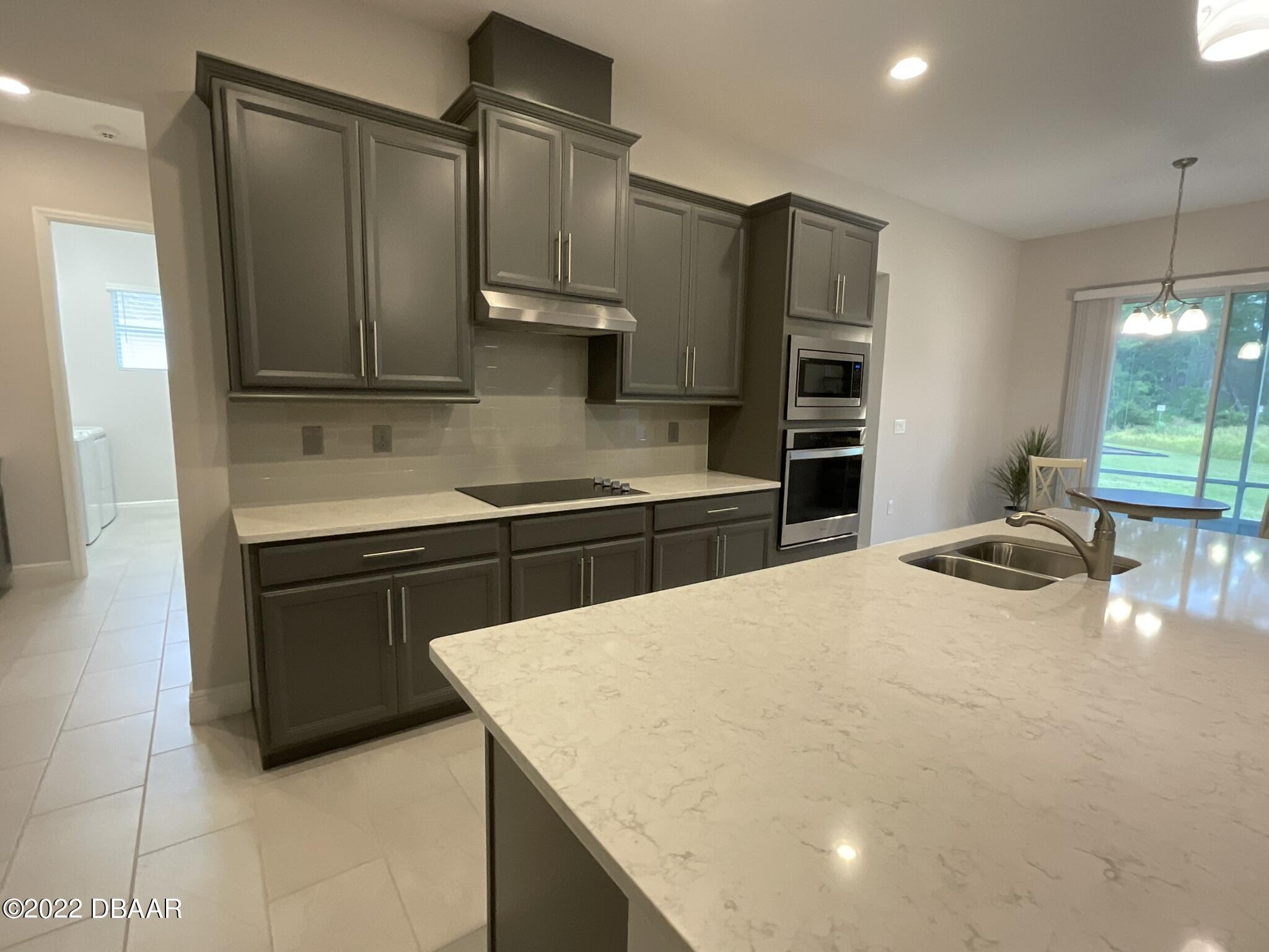 283 Cypress Trail Drive Ormond Beach, FL 32174 - Photo 5 of 28 a kitchen with stainless steel appliances a sink cabinets and wooden floor