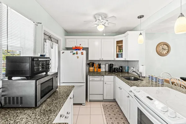 a kitchen with granite countertop a sink appliances and cabinets