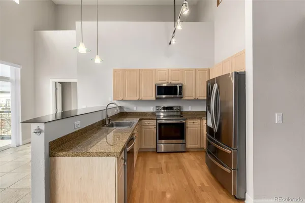 a kitchen with stainless steel appliances granite countertop a refrigerator a stove a sink and a microwave