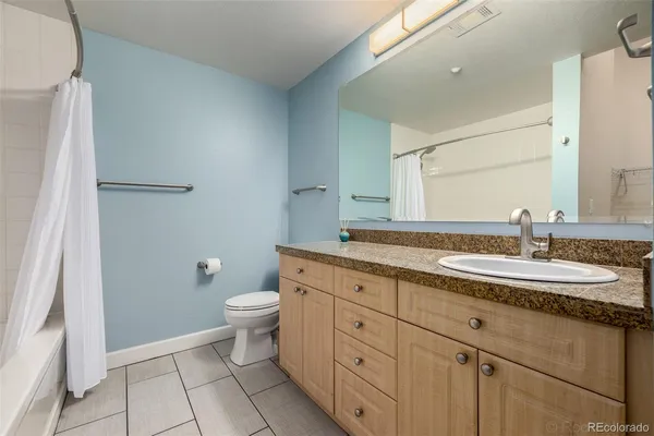 a bathroom with a granite countertop sink a toilet and a mirror