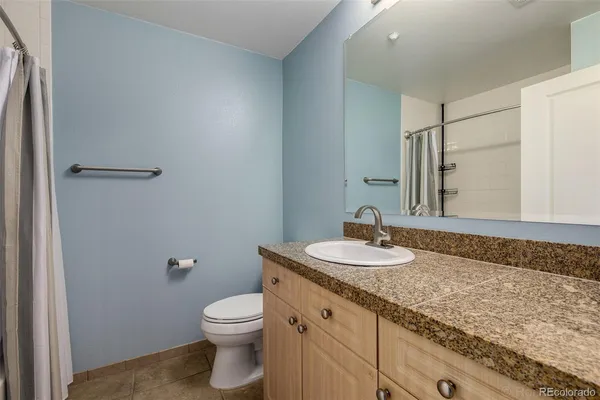 a bathroom with a granite countertop toilet a sink and a mirror