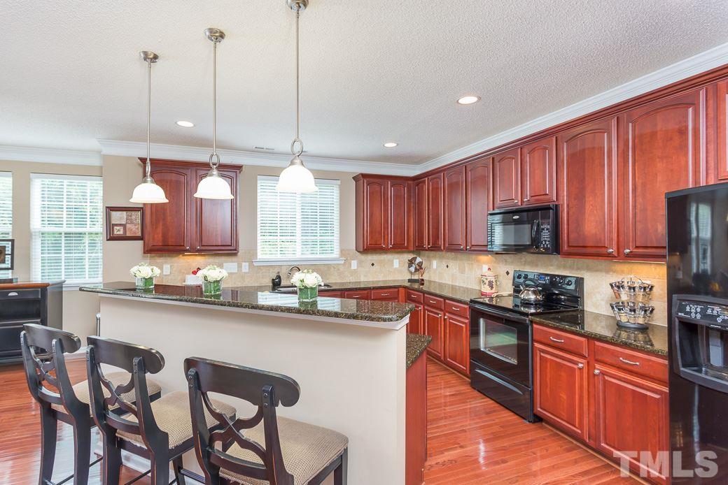 5716 Sea Fox Court Raleigh, NC 27616 - Photo 2 of 23 a kitchen with stainless steel appliances granite countertop wooden cabinets a sink a stove a dining table and chairs