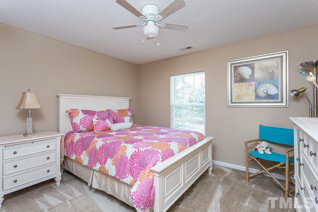 5716 Sea Fox Court Raleigh, NC 27616 - Photo 16 of 23 a bedroom with a bed and a chandelier