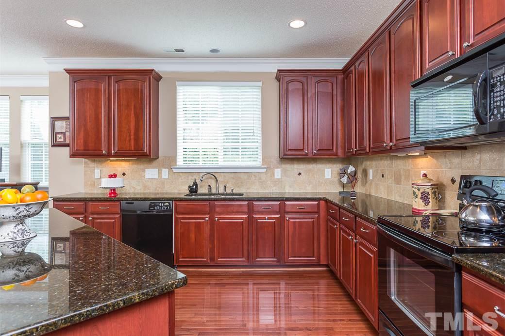 5716 Sea Fox Court Raleigh, NC 27616 - Photo 4 of 23 a kitchen with stainless steel appliances granite countertop wooden cabinets a stove top oven a sink and dishwasher with wooden floor
