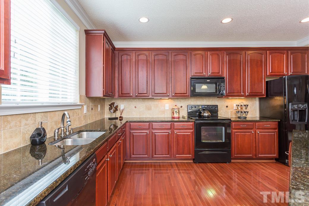 5716 Sea Fox Court Raleigh, NC 27616 - Photo 5 of 23 a kitchen with stainless steel appliances granite countertop a stove top oven a sink dishwasher and a refrigerator with wooden cabinets