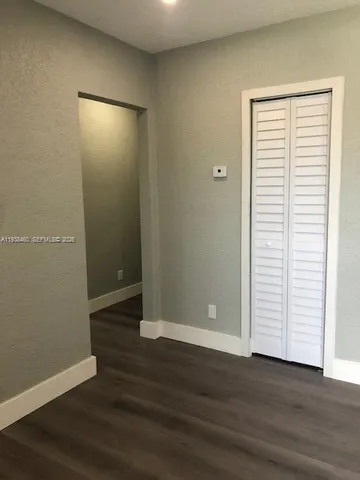 an empty room with wooden floor and mirror