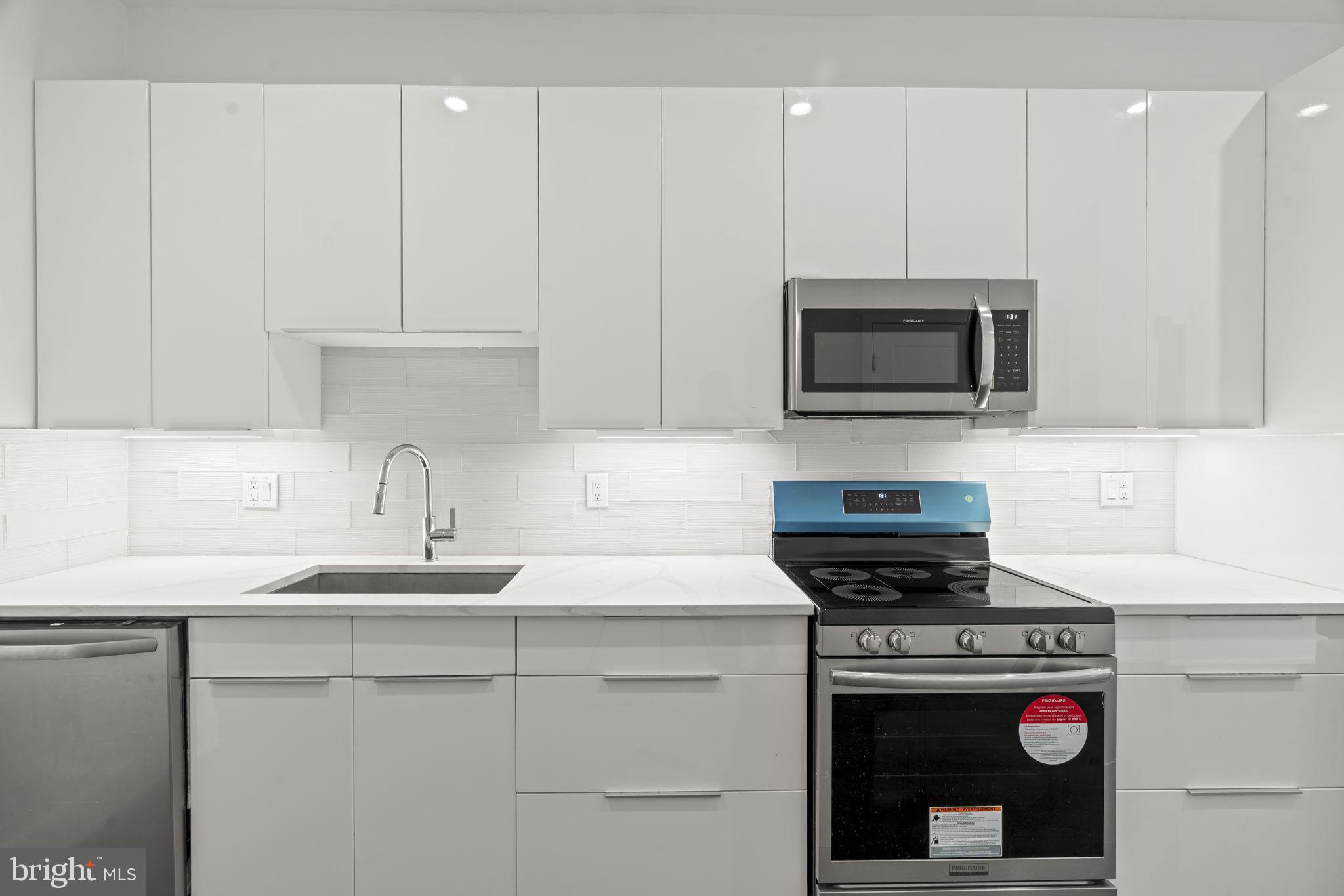1244 South 20th Street, Unit 2 Philadelphia, PA 19146 - Photo 9 of 28 a kitchen with granite countertop a sink stove and microwave