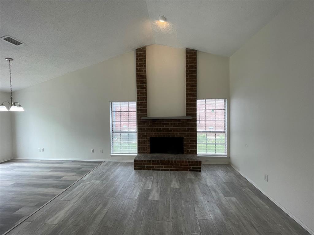 9415 Rutherglen Drive Dallas, TX 75227 - Photo 5 of 18 an empty room with wooden floor fireplace and windows