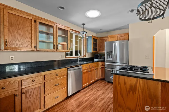 a kitchen with granite countertop a refrigerator a sink and wooden cabinets