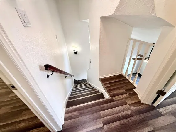 a view of staircase with wooden floor and white walls