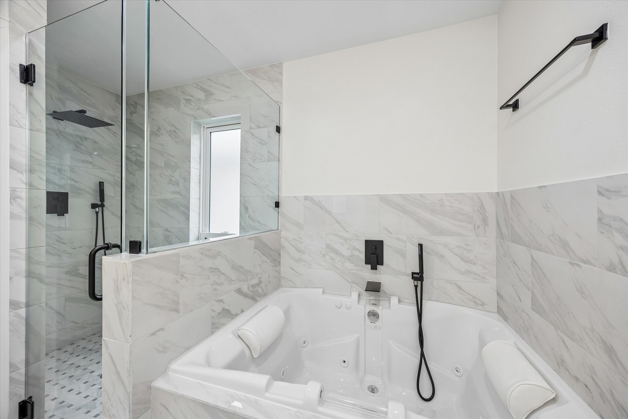 1420 Indiana Street Houston, TX 77006 - Photo 19 of 31 This modern bathroom features a sleek glass-enclosed shower with a rainfall showerhead and a luxurious spa-like jacuzzi tub, both set against elegant marble tile walls.