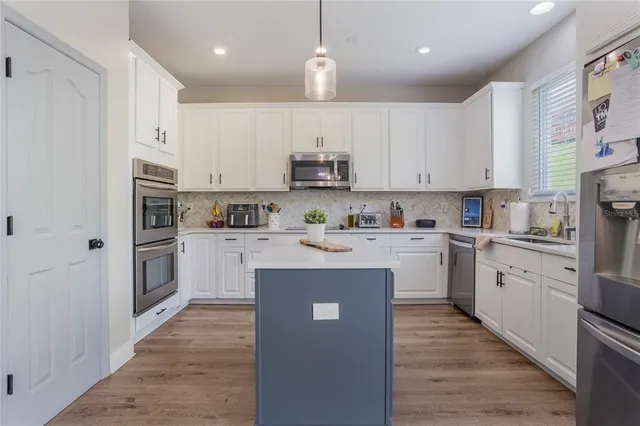 a kitchen with granite countertop a refrigerator stove top oven and cabinets