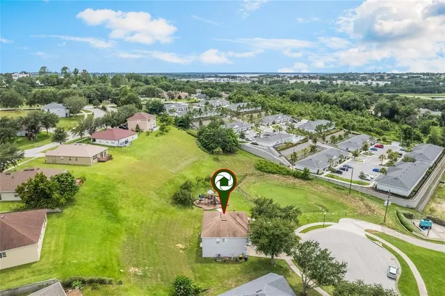 an aerial view of a residential houses with outdoor space and trees all around