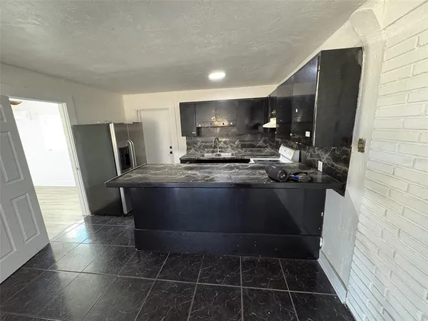 a kitchen with stainless steel appliances kitchen island granite countertop a refrigerator a stove and a sink