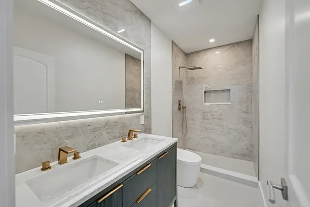 a bathroom with a granite countertop sink a toilet and shower