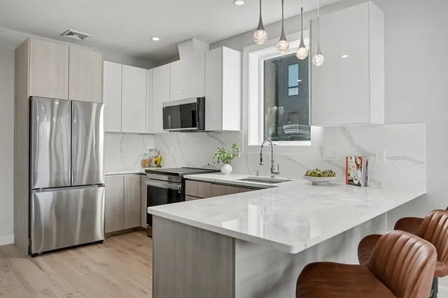 a kitchen with stainless steel appliances a sink a stove a refrigerator cabinets and a dining table