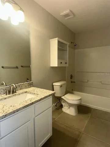 a bathroom with a granite countertop toilet a sink and a bathtub