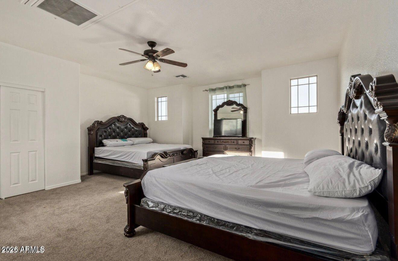 9171 West Berkeley Road Phoenix, AZ 85037 - Photo 20 of 36 a bedroom with a bed and a chandelier