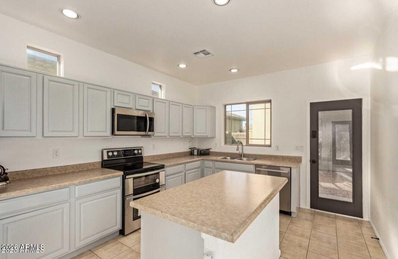 9171 West Berkeley Road Phoenix, AZ 85037 - Photo 6 of 36 a kitchen with stainless steel appliances granite countertop a sink stove and refrigerator